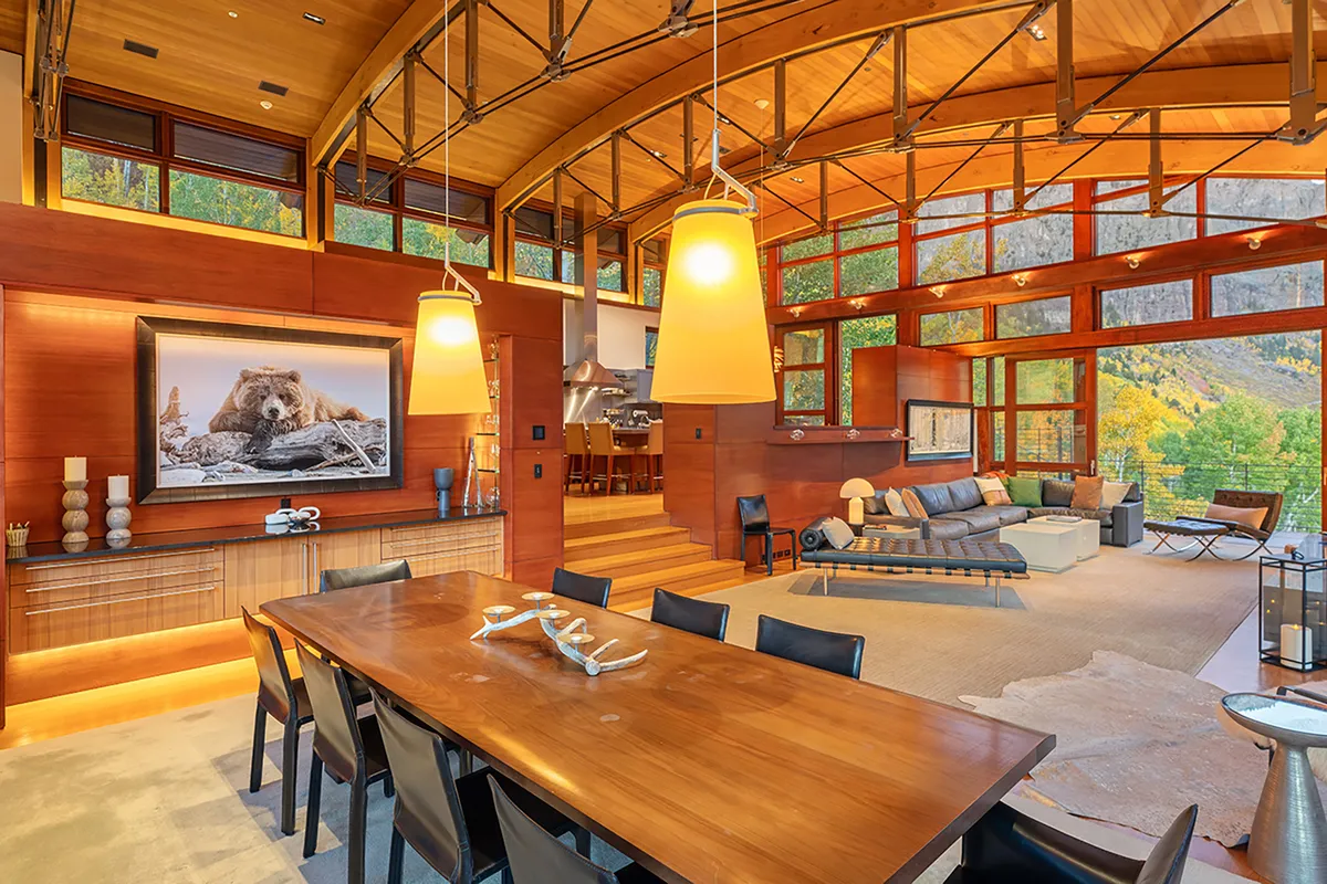 This interior image highlights a contemporary dining table with elegant chairs, set against a dramatic bear photograph and flanked by floor-to-ceiling windows. The modern sofa and artistic light fixtures contribute to a welcoming, stylish ambiance ideal for hosting family or guests.